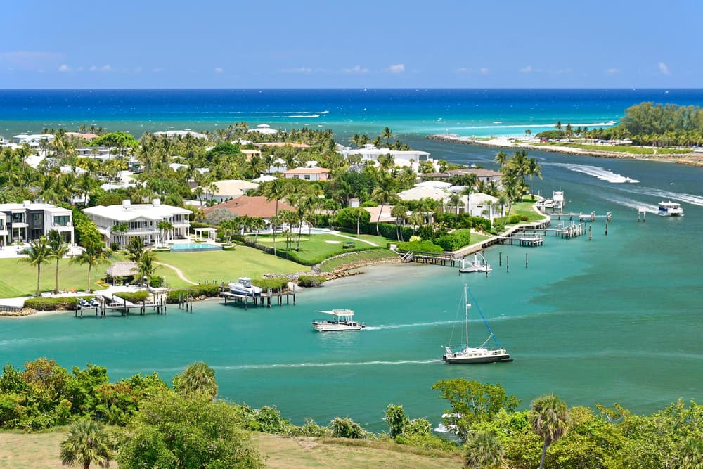 Aerial view of coastal Florida waterfront homes with turquoise water and sailboats